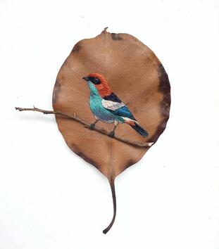 Артистка бродира птици върху сухи листа